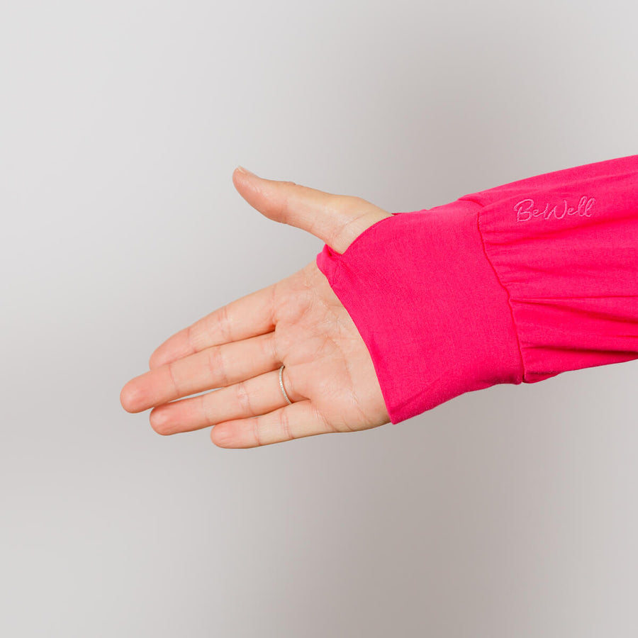 Woman wearing bright pink Bamboo IV zip hoodie with left sleeve zipper open for medical access.