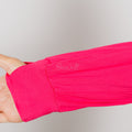 Person wearing bright pink bamboo IV zip hoodie showing left sleeve access zipper detail.