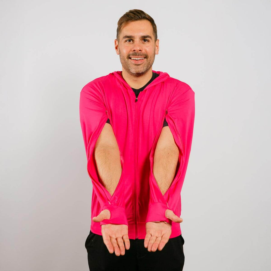 Man wearing a bright pink jacket with cut-out sleeves on a plain background