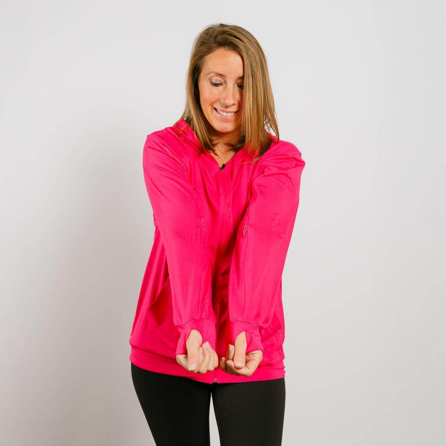 Woman wearing bright pink zip hoodie with arms crossed in front view.