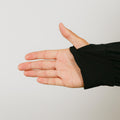 Open palm hand wearing black sleeve against light gray background.