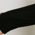 Black zip hoodie worn on arm showing embroidered logo detail on sleeve.