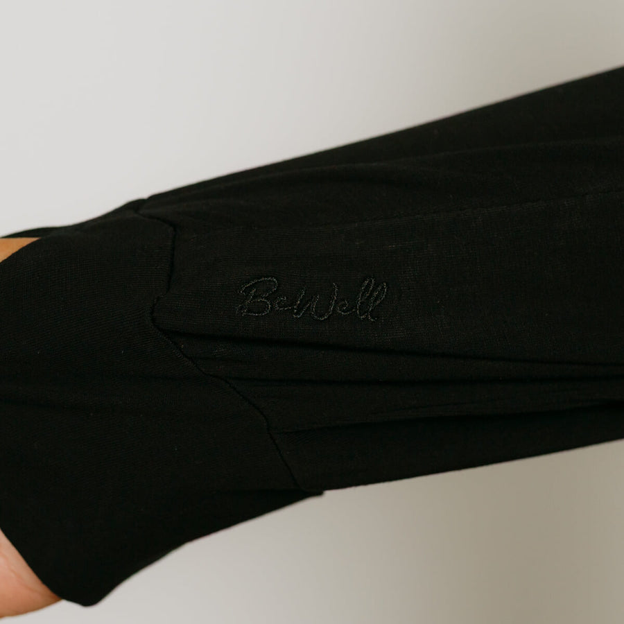 Black zip hoodie worn on arm showing embroidered logo detail on sleeve.