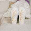 Close-up of white crew socks with gold "thrive" text displayed on soles.