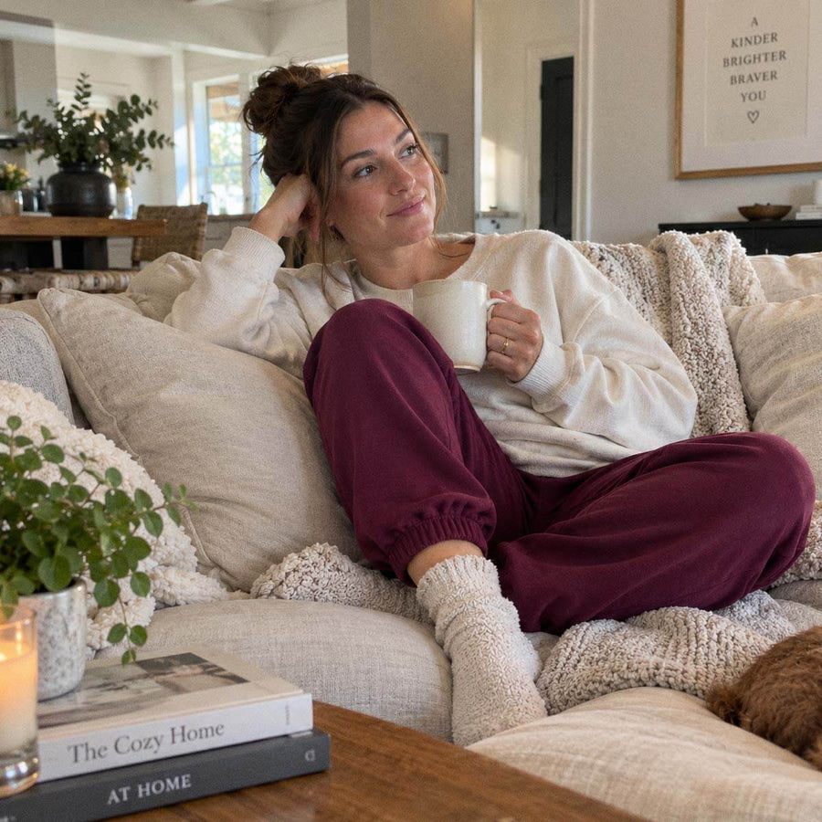 Woman relaxing on a cozy couch in BeWell sweatpants during a rest and recovery day