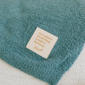Close-up of teal infusion blanket with inspirational message label on soft fabric.