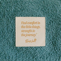 Close-up of inspirational quote patch on teal infusion day blanket.