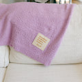 Lavender and cream Infusion Day Blanket draped over white cushioned furniture, detail view.