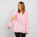 Woman wearing pink crewneck sweatshirt with cutout sleeve detail over black pants. | Model is 5'3" 130lbs wearing size S
