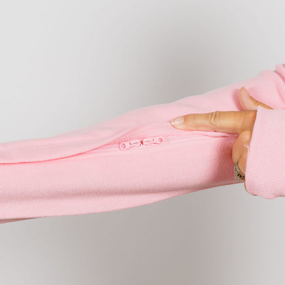 Hand holding open a pink crewneck sweatshirt to display an interior zipper pocket detail.