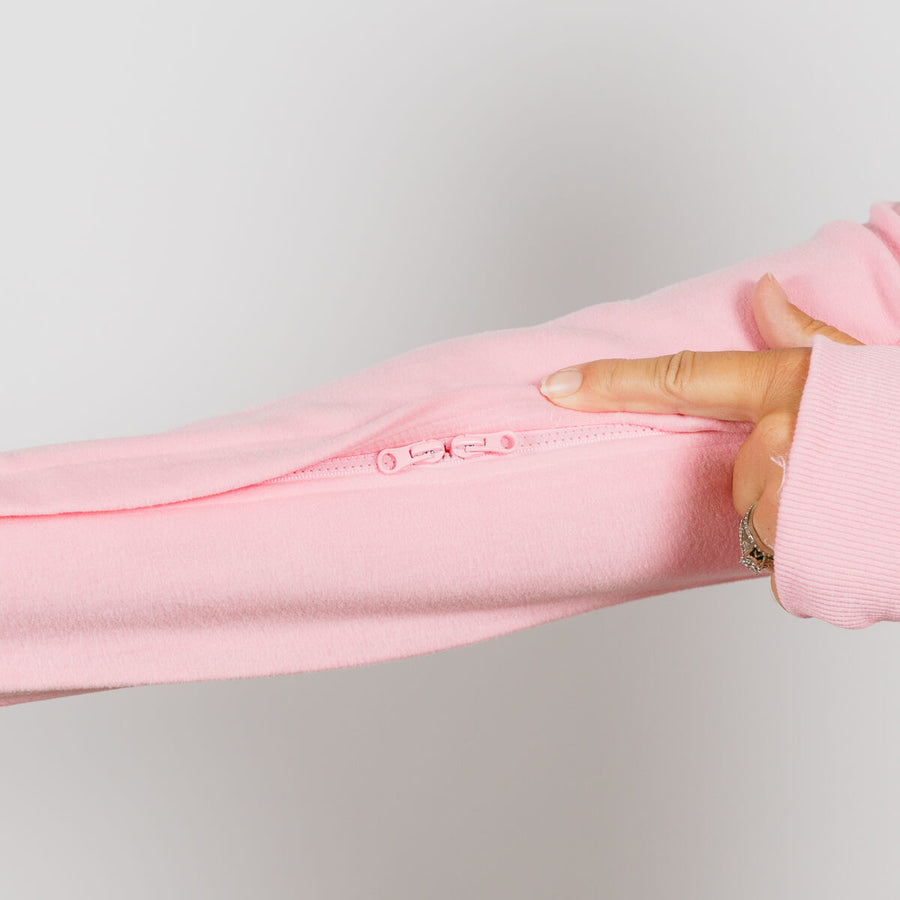 Hand holding open a pink crewneck sweatshirt to display an interior zipper pocket detail.
