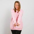 Woman wearing a pink crewneck sweatshirt over black leggings, smiling with hands extended downward.