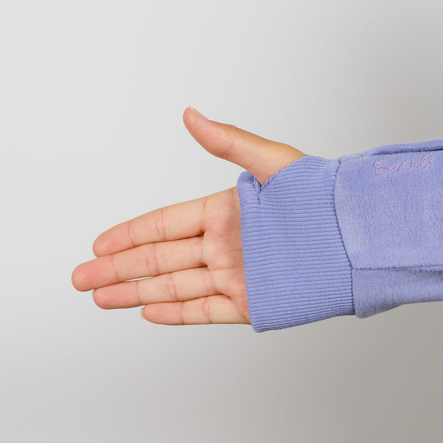 Woman's hand and arm wearing a light purple crew neck sweatshirt against a gray background.