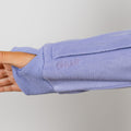 Person wearing a light purple crewneck sweatshirt with ribbed cuffs and collar detail.