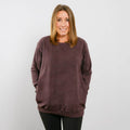 Woman wearing burgundy IV crewneck sweatshirt, front view, standing against white background.
