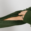 Person wearing olive green crewneck with dual arm zippers open for access.