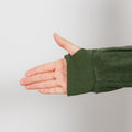 Person wearing olive green IV crewneck with arm extended showing ribbed cuff detail.