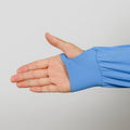 Person wearing a blue quarter zip with hand extended, showing the cuff detail against a gray background.