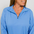 Woman wearing a light blue quarter-zip pullover with long sleeves and a collar.