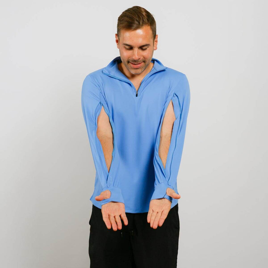 Man wearing light blue quarter-zip hoodie with thumb holes and black pants against white background.