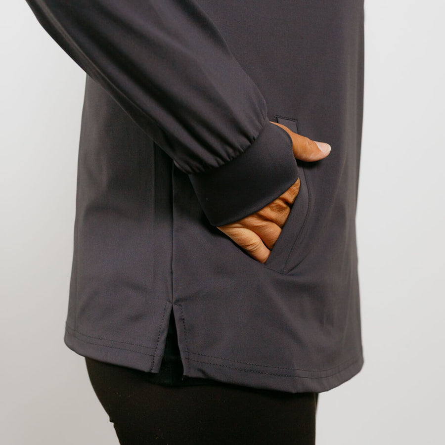 Person wearing charcoal quarter zip jacket with hands in pockets lined with tan fleece.