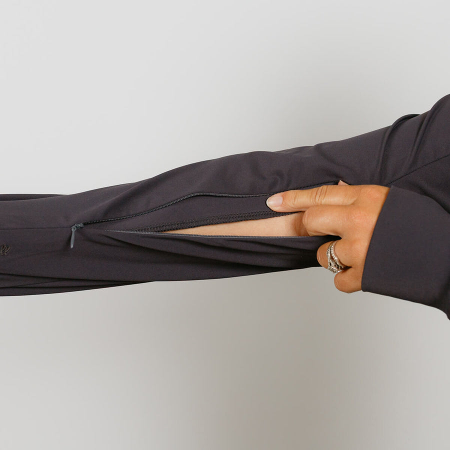 Person wearing charcoal gray quarter zip jacket with hand pulling sleeve zipper closed.