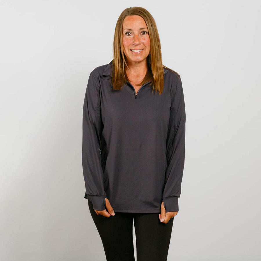 Woman wearing a charcoal quarter zip pullover with orange accents over black pants.