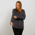 Woman wearing a dark navy quarter-zip pullover and black pants, smiling while looking down.