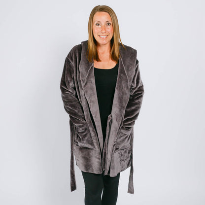 Woman wearing a gray velvet hooded robe over a black shirt against a white background.