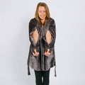Woman wearing a gray velvet hooded robe with cutout sleeves over black leggings.