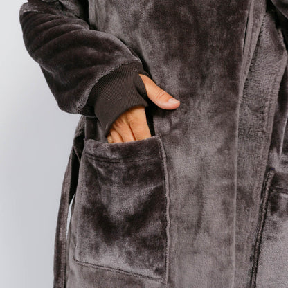 Hand resting in front pocket of charcoal velvet robe with ribbed cuff detail.