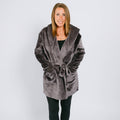 Woman wearing a gray velvet hooded robe with tie waist over black clothing.