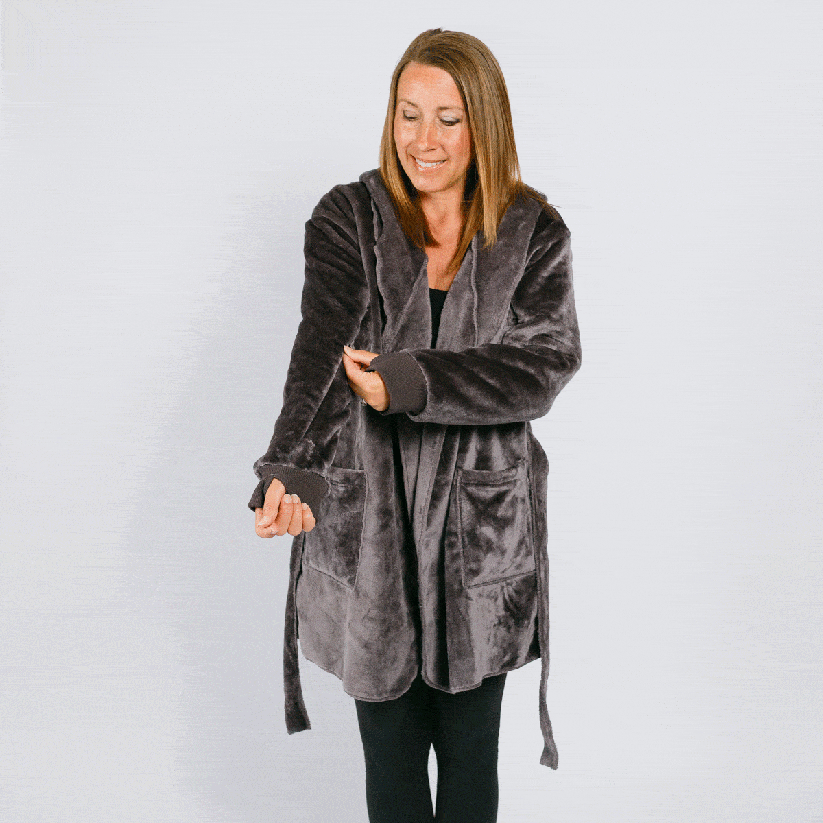 Woman wearing a gray velvet robe over black clothing against a white background.