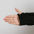 Person's hand extended palm-up wearing black ribbed sleeve cuff against gray background.