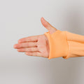Person wearing peach IV zip hoodie displaying left arm zipper access opening.