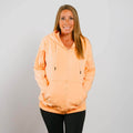 Woman wearing peach IV zip hoodie with front zipper, standing against white background.