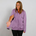 Woman wearing a lavender purple zip-up hoodie over black pants, smiling while looking downward.