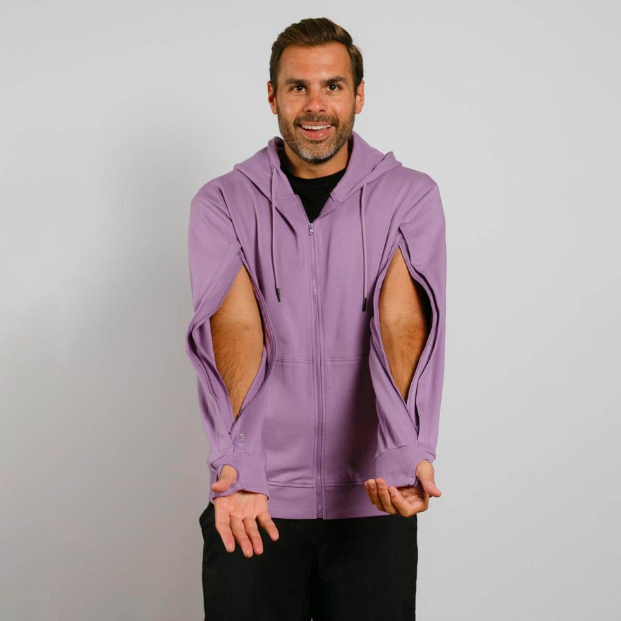 Man wearing purple zip hoodie with cutout arm holes over black shirt, smiling at camera.
