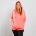 Woman wearing coral pink zip hoodie with front view showing full-length design and hood.