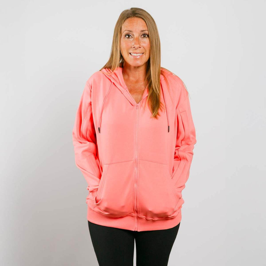 Woman wearing coral pink IV zip hoodie with front zipper, front view.