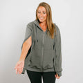 Woman wearing gray zip hoodie with left arm zipper access feature visible during treatment.