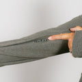 Woman wearing sage green IV zip hoodie demonstrating left sleeve zipper access feature.