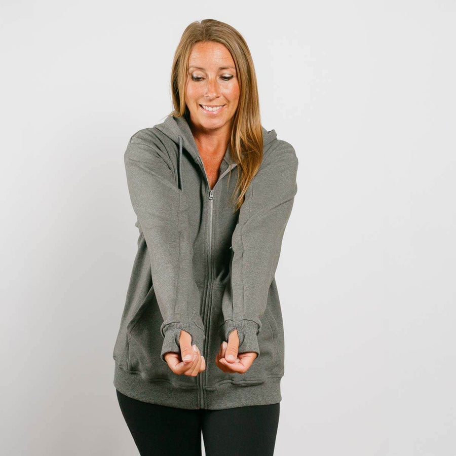 Woman wearing gray zip hoodie with adaptive sleeves, front view smiling.