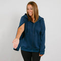 Woman wearing a navy blue zip-up hoodie with short sleeves over black pants, smiling downward.