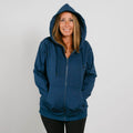 Woman wearing a navy blue zip-up hoodie with hood up, smiling at camera against white background.