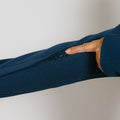 Hand demonstrating the side zipper pocket detail on a navy blue zip hoodie.