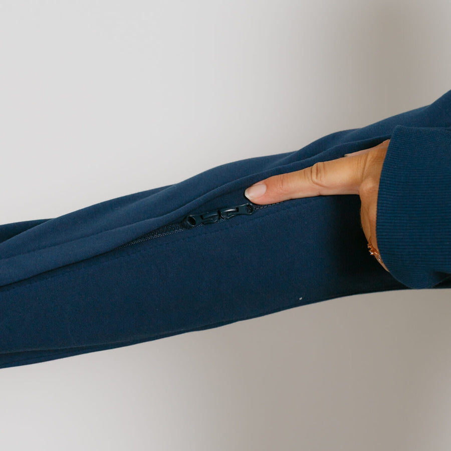 Hand demonstrating the side zipper pocket detail on a navy blue zip hoodie.