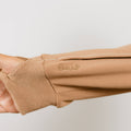 Close-up of tan IV zip hoodie sleeve showing ribbed cuff detail and zipper access on arm.