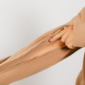 Woman wearing tan IV zip hoodie, close-up showing left sleeve zipper access detail.