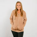 Woman wearing tan IV zip hoodie with front zipper, hands in pockets, front view.